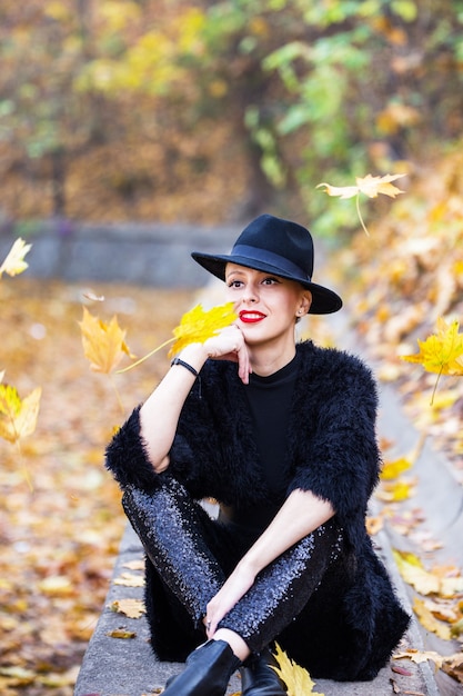 Belle femme élégante dans un chapeau noir en automne parc