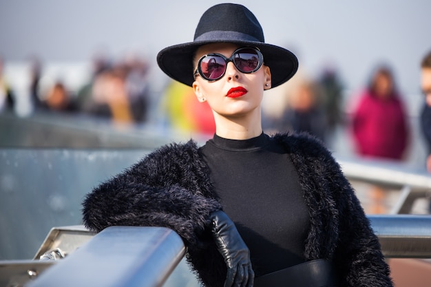 Belle femme élégante dans un chapeau noir sur le pont de verre