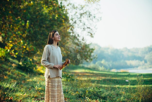 Belle femme élégante debout dans un parc d'automne femme marchant et profitant de la nature d'automne en plein air