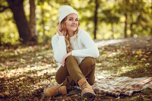 Belle femme élégante debout dans un parc à l'automne.