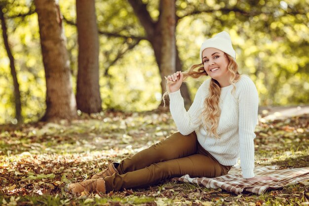 Belle femme élégante debout dans un parc à l'automne.