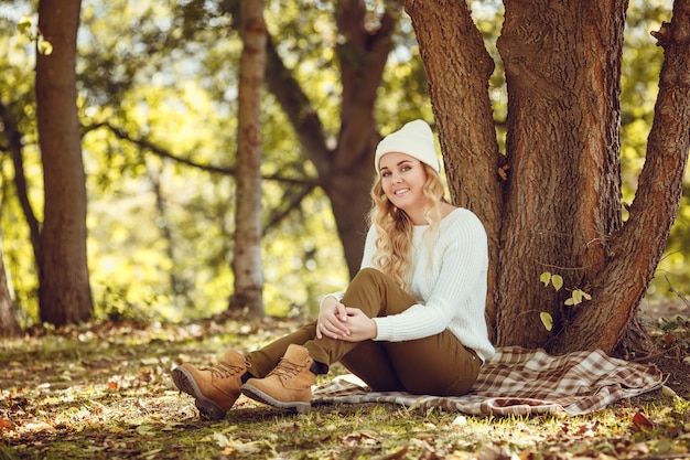 Belle femme élégante debout dans un parc à l'automne.