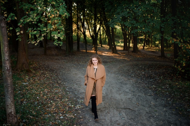 Belle femme élégante, debout dans un parc en automne