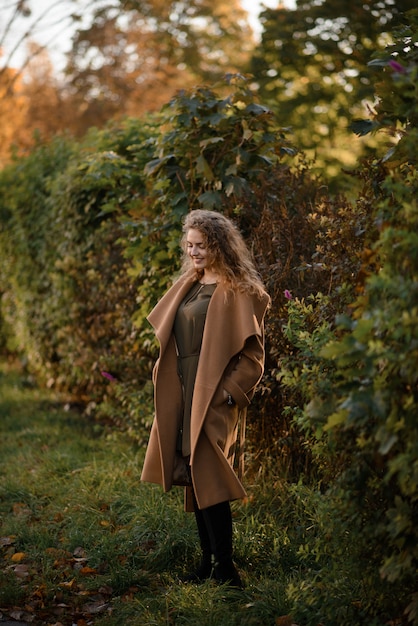 Belle femme élégante, debout dans un parc en automne