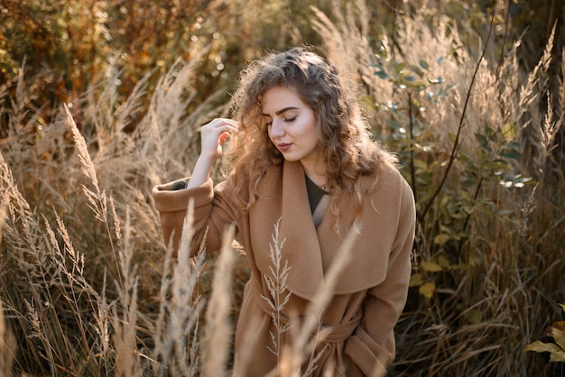 Belle femme élégante, debout dans un parc en automne