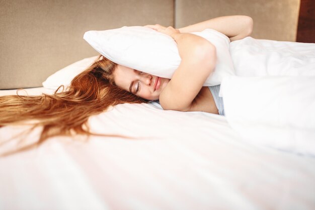 Belle femme embrasse l'oreiller, se réveillant. Literie du matin à la maison, détente dans la chambre