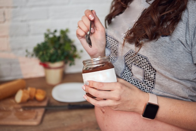 Belle femme enceinte appréciant manger de la pâte de chocolat