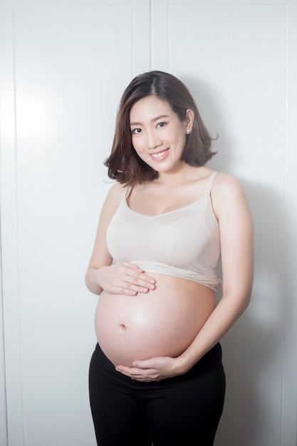 Belle femme enceinte asiatique attend bébé et touche son ventre