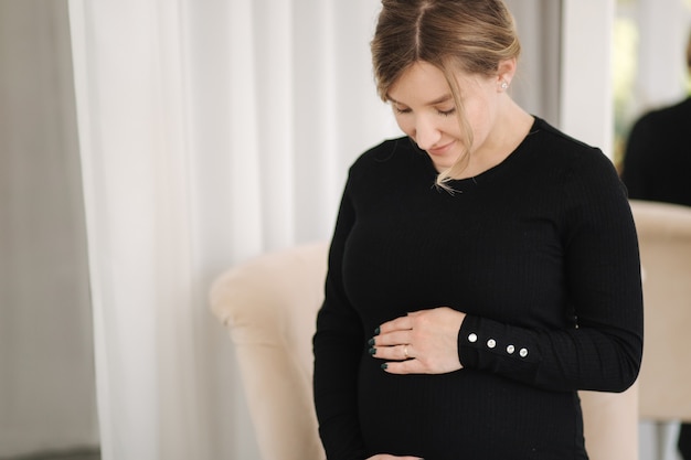 Belle femme enceinte assise sur une chaise à la maison femme attendant bébé