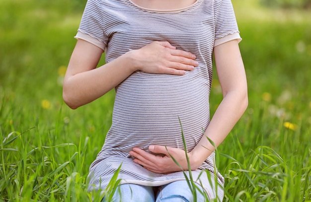 Belle femme enceinte assise sur l'herbe