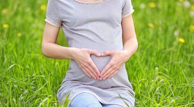 Belle femme enceinte assise sur l'herbe