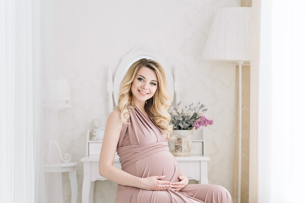 Belle femme enceinte blonde à l'intérieur