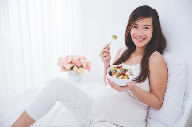 Belle femme enceinte avec un bol de fruits