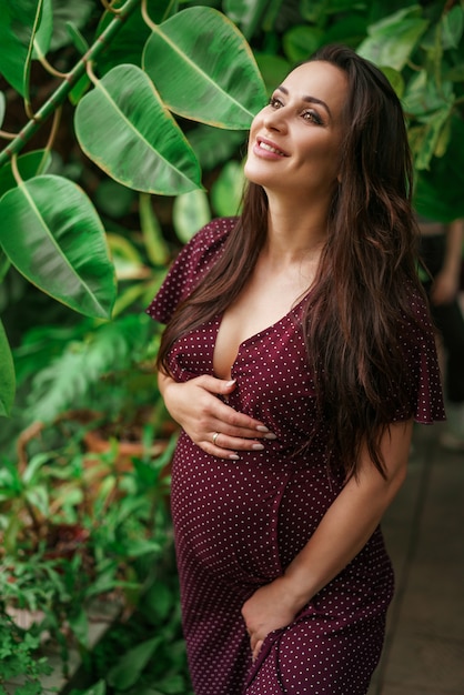 Belle femme enceinte sur les feuilles vertes, beaux yeux heureux