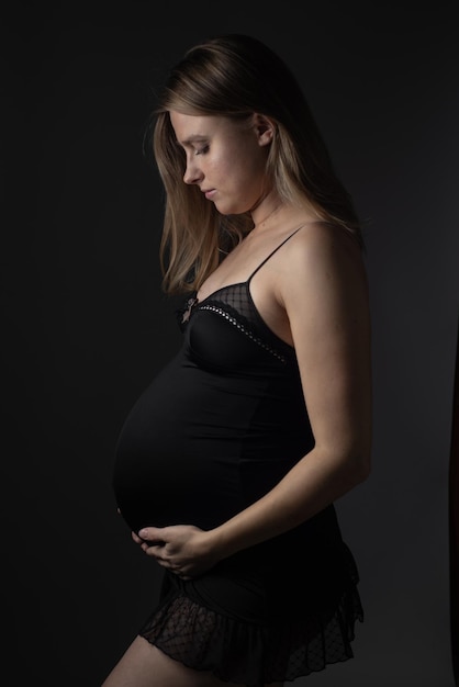 Belle femme enceinte sur fond sombre