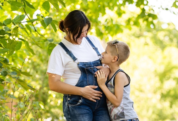 Belle femme enceinte et mère avec son fils mignon tout-petit s'amuser dans le parc d'été.