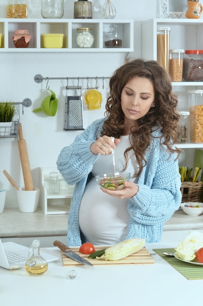 Belle femme enceinte avec de la nourriture à la cuisine