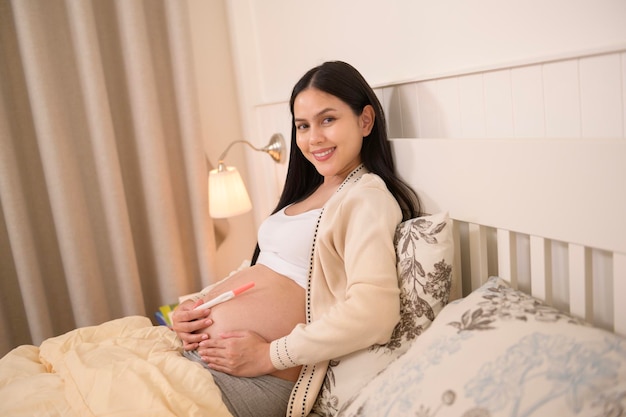 Une belle femme enceinte qui tient un test de grossesse positif fertilité infertilité