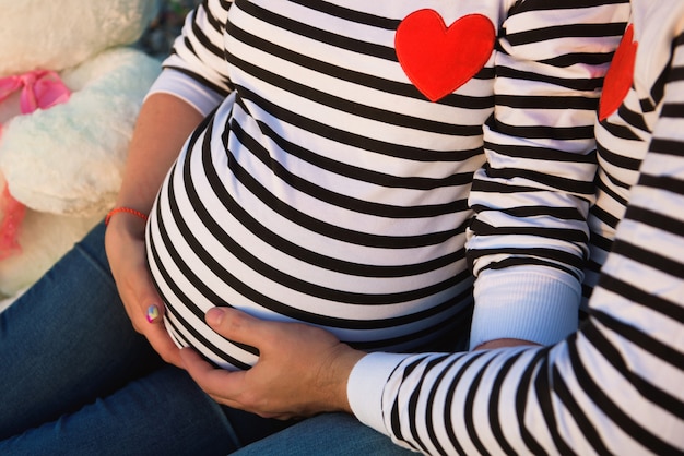 Belle femme enceinte avec sa famille assise au bord de la rivière.