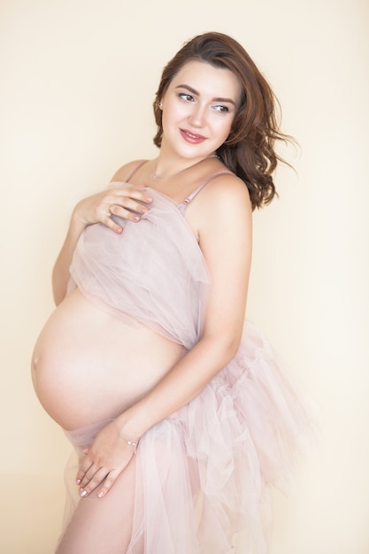 Belle femme enceinte sur scène neutre. Image gros plan dans l'expectative.