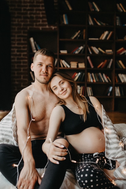 Belle femme enceinte et son beau mari sourient tout en passant du temps ensemble au lit