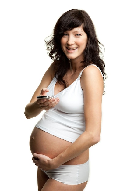 Belle femme enceinte souriante tenant un téléphone portable dans sa main