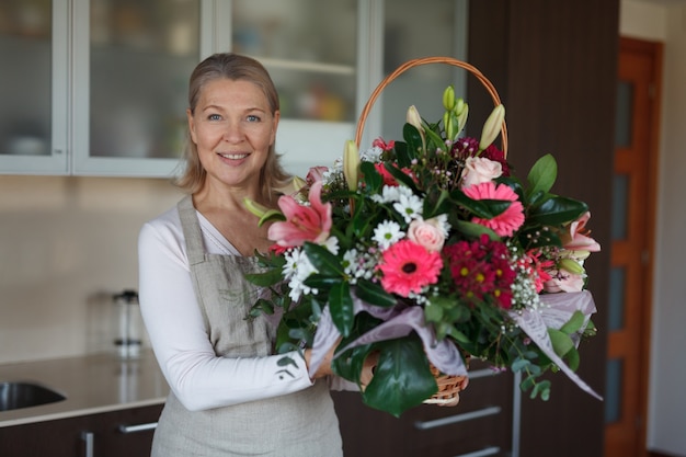 Belle femme avec un énorme bouquet de fleurs dans sa cuisine.