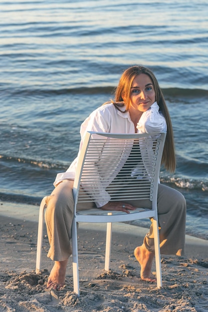 Une belle femme est assise sur une chaise près de la mer