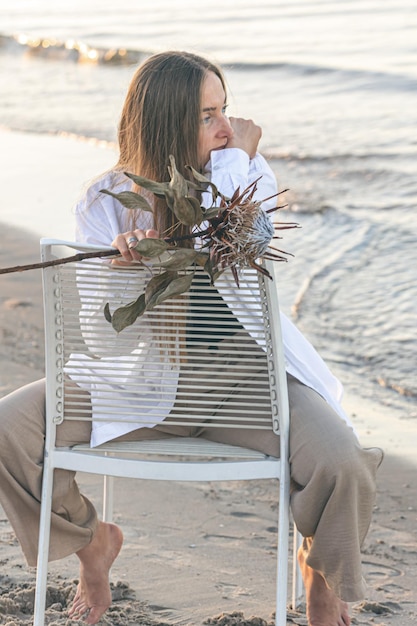 Une belle femme est assise sur une chaise près de la mer