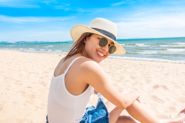 Belle femme est assise sur la plage