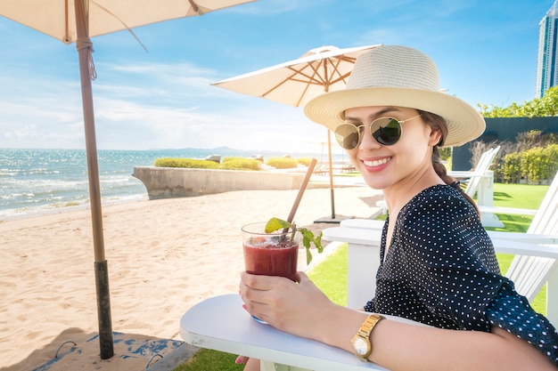 Belle femme est relaxante sur la plage, sous un parasol