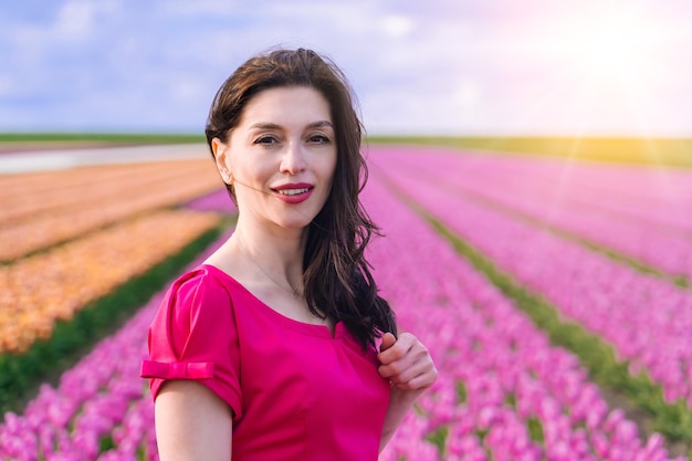 Belle femme en été dres debout dans les champs de fleurs de tulipes colorées