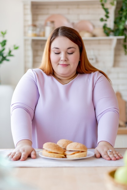 Belle femme excitée regardant les hamburgers tout en voulant les manger