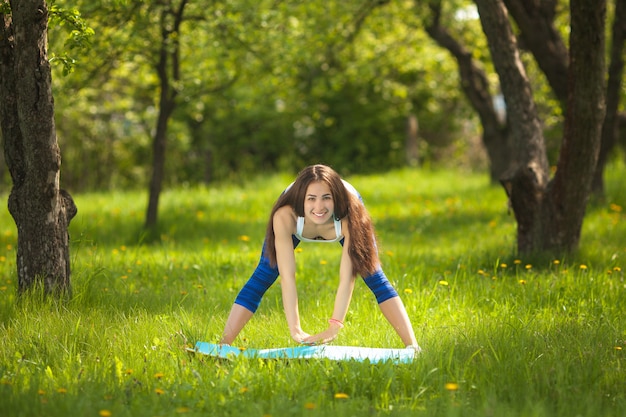 Belle femme exerçant à l'extérieur. Joyeuse fille mince faisant de l'exercice dans le parc en été