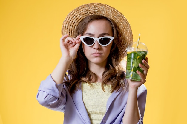 Belle femme expressive posant avec un verre de boisson