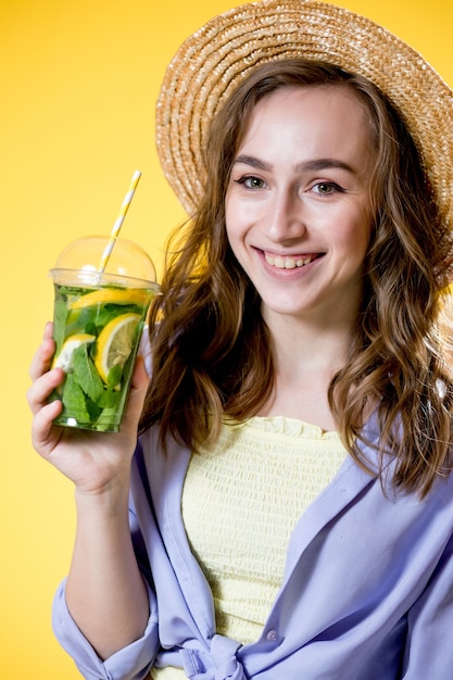 Belle femme expressive posant avec un verre de boisson