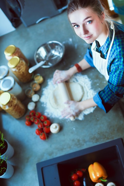 Belle femme faisant cuire le gâteau dans la cuisine debout près du bureau.