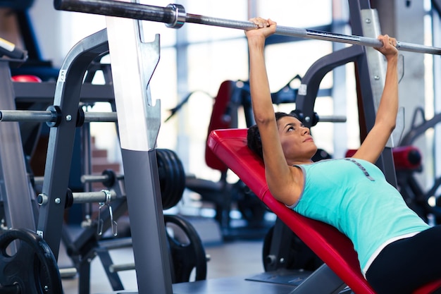 Belle femme faisant des exercices avec haltères sur le banc dans la salle de fitness