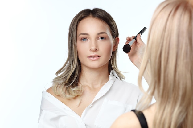 Belle femme faisant le maquillage de soirée et tenant la brosse de maquillage