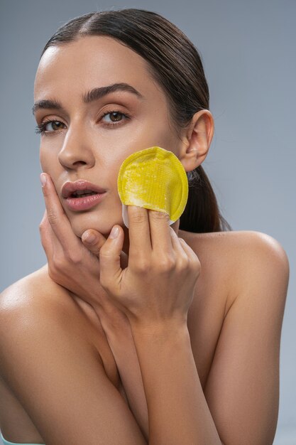 Belle femme faisant le nettoyage du visage avec un gant de toilette