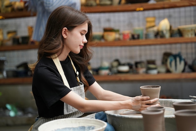 Belle femme faisant de la poterie en céramique sur les mains de la roue closeup femme en passe-temps d'affaires indépendant