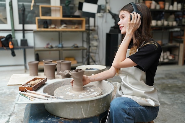 Photo belle femme faisant de la poterie en céramique sur les mains de la roue closeup femme en passe-temps d'affaires indépendant