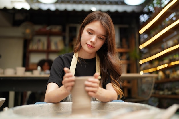 Belle femme faisant de la poterie en céramique sur les mains de la roue closeup femme en passe-temps d'affaires indépendant