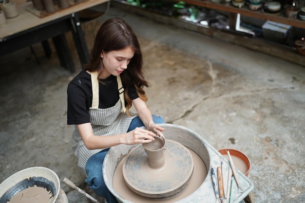 Belle femme faisant de la poterie en céramique sur les mains de la roue closeup femme en passe-temps d'affaires indépendant