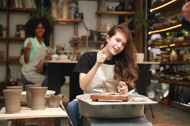 Belle femme faisant de la poterie en céramique sur les mains de la roue closeup femme en passe-temps d'affaires indépendant