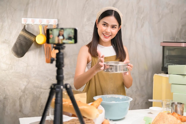 Belle femme fait de la boulangerie tout en diffusant en direct ou en enregistrant une vidéo sur les réseaux sociaux dans son concept d'entreprise de café maison