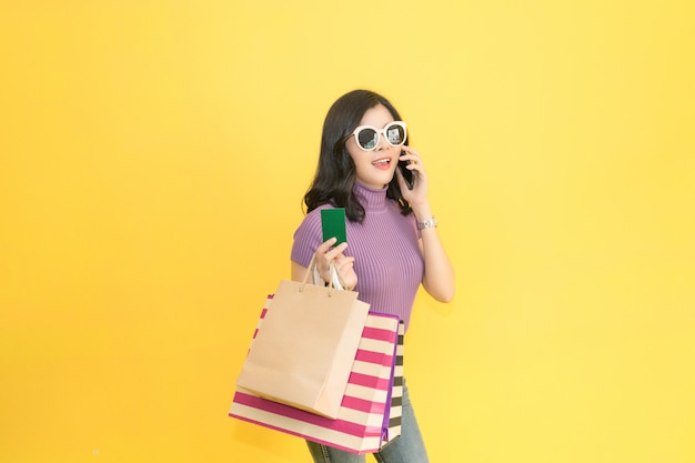 Belle femme fait du shopping dans le centre commercial en utilisant la carte de crédit. Femme portant des lunettes et tenant la mode sac à provisions dans le magasin.