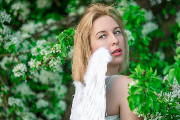 Belle femme féminine aux ailes blanches avec des fleurs printanières blanches