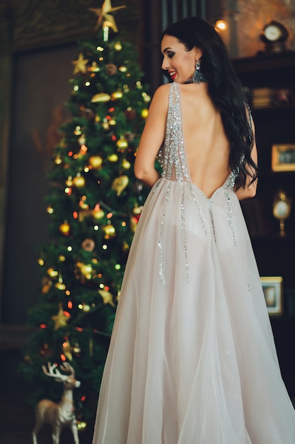 Belle femme fille dans le studio du nouvel an posant, séance photo photo nouvel an. Belle fille dans une robe luxueuse aux jambes élancées. Noël, hiver, concept de bonheur.