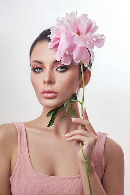 Belle femme avec une fleur rose à la main